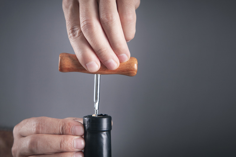 Man opening bottle of wine with corkscrew